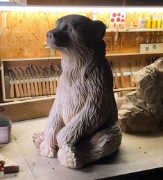 a sculpture of a dog sitting on top of a table next to tools and knives