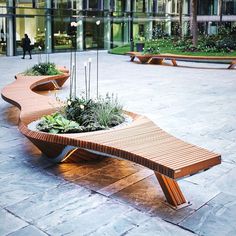 two benches with plants in them sitting on the ground next to each other near a building