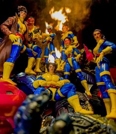 a group of action figures sitting on top of each other in front of a fire