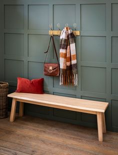 a wooden bench sitting next to a wall with a purse hanging on it's side