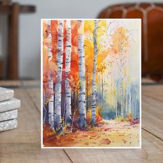 a card with watercolor trees on it sitting on a table next to stacks of coasters