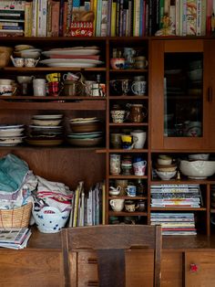 a wooden cabinet filled with lots of books and bowls on top of it's shelves