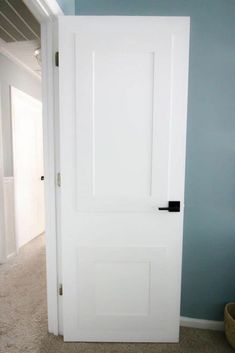 an open white door in a room with carpeted flooring and blue paint on the walls