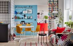 a living room filled with furniture and colorful decor on the walls in front of a blue wall