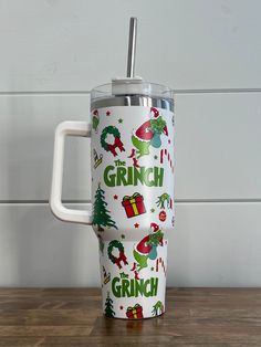 a white coffee cup with green and red christmas designs on it sitting on a wooden table