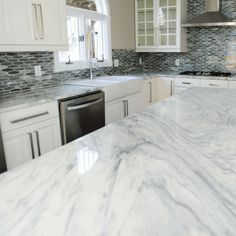 a kitchen with marble counter tops and white cabinets