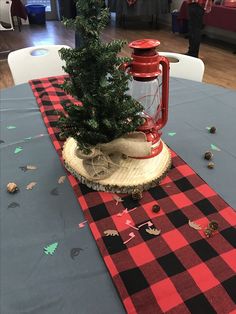 a small christmas tree sitting on top of a wooden log next to a red lantern