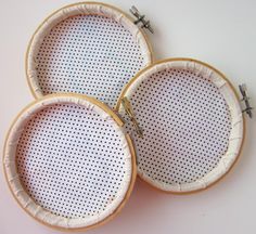 three embroidery hoop holders on a white surface with pins in the middle and holes in the bottom