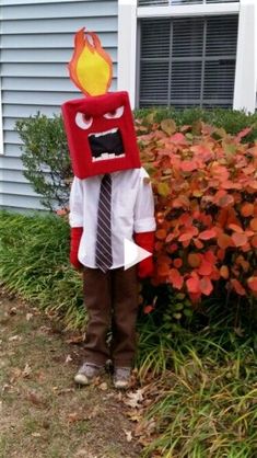 a young boy dressed up as a fireman standing in front of a bush and bushes