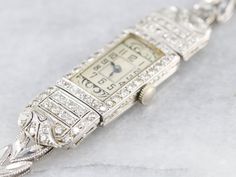 "This Retro Era ladies wrist watch is crafted of platinum and white gold, and inlayed with diamonds. The glittering diamonds turn this from a time piece into a piece of fine ladies jewelry. This beautiful ladies wrist watch is in excellent condition and, like all of our watches, has been restored and cleaned by a master watch craftsman. The original quartz movement and band has been replaced. We left the original engraving on the reverse \"BERTHA E. GILSON\" as a sentiment to its history! Materi Art Deco Diamond Watch For Evening, Wedding Platinum Diamond Watch With 17 Jewels, Art Deco Platinum Watch With Diamond Accents, Art Deco Platinum Watch For Anniversary, Art Deco Platinum Diamond Watch In White Gold, Silver Diamond Watch For Wedding, Art Deco White Gold Platinum Diamond Watch, Art Deco Platinum Anniversary Watch, Platinum Diamond Watch With Single Cut Diamonds For Wedding