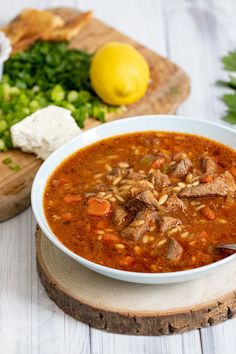 a white bowl filled with soup sitting on top of a wooden cutting board