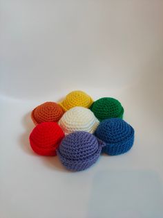 there are many crocheted balls on the white table top, all in different colors