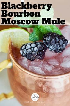 the blackberry bourbon moscow mule is garnished with lime and blackberries in a copper mug