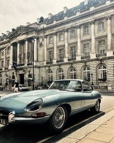 an old car parked in front of a large building on the side of the road