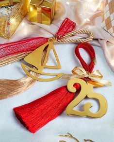 two gold and red ornaments on a white surface with presents in the backgroud