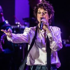 a woman in white shirt and tie singing into microphone