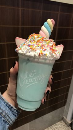 a person holding up a cup with ice cream and sprinkles on it