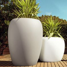 two large white planters sitting on top of a wooden deck