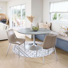 a living room filled with furniture and a round table in the middle of a wooden floor