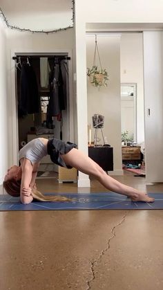 a woman is doing yoga on a mat in the middle of a room with a mirror