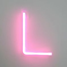 a pink neon sign on a white wall in the shape of a letter l is lit up