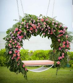 a swing with flowers hanging from it in the grass