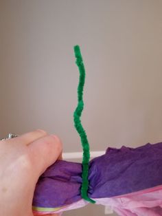 someone is making something out of tissue paper with green thread on the top and bottom