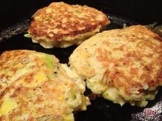 three crab cakes cooking in a cast iron skillet