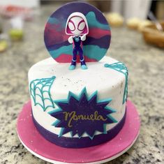 there is a cake with a spiderman figure on the top and purple frosting