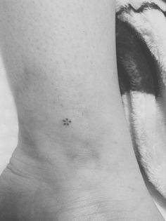 a black and white photo of a person's foot with a tiny flower on it