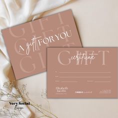 two gift certificates sitting next to each other on a white table cloth with flowers