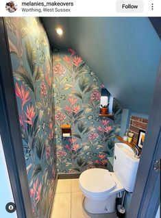 a toilet and sink in a small room with wallpaper on the walls behind it