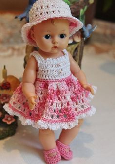 a small doll wearing a pink dress and hat