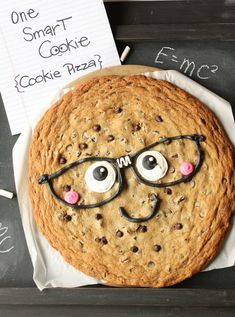 a chocolate chip cookie with eye glasses and a sign that says, one smart cookie cookie pizza?