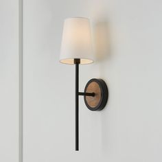 a wall light with a white shade on it's side and a black arm