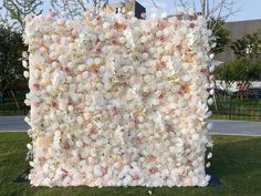 a large white and pink flowered wall in the grass