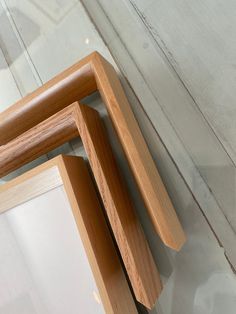 three wooden frames sitting on top of a white floor next to each other in front of a mirror