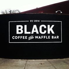 black coffee and waffle bar sign in front of a brick wall with white lettering