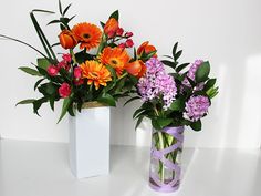 two vases filled with different colored flowers on a white counter top next to each other