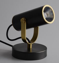 a black and gold desk lamp with a metal base on a gray background, the light is dimmed