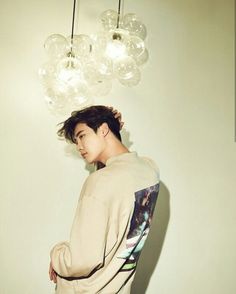 a young man standing under a chandelier with lights hanging from it's ceiling