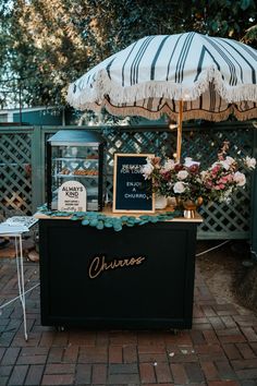 an umbrella that is sitting on top of a table with flowers and other items under it