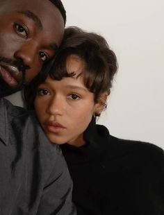 a man and woman posing for the camera with their arms around each other's shoulders