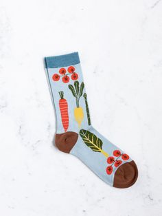 a blue sock with carrots, radishes and flowers on it sitting on a marble surface