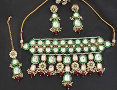 Get ready to fall in love with our exquisite green-Ruby gold Kundan Necklace Set, embellished with Meena work and Clustered Ruby Drops. This stunning set also includes matching Maang tikka and Earrings, making it the ultimate addition to your jewelry collection.  This exquisite set will add a touch of royalty to your style. Hurry, this deal won't last long! PRODUCT VARIATIONS - We strive to present each product with utmost accuracy and detail. However, due to the photography process, the item size may seem bigger or smaller than it actually is. So, we strongly suggest that you check the measurements provided in each listing. Also, it's important to note that the color, shade, and texture seen in the product images may slightly differ from the actual product due to the limitations of digita Gold Kundan Necklace, Kundan Necklace Set, Gold Jewellry, Earrings Making, Maang Tikka, Kundan Necklace, Kundan Necklaces, Choker Necklaces, Necklace Set