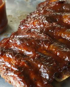 ribs covered in bbq sauce next to a glass of barbecue sauce