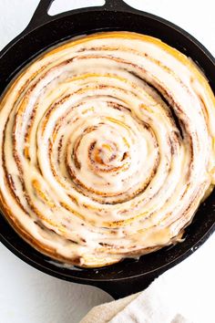 a skillet filled with cinnamon rolls on top of a white table