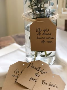 three tags with flowers in them sitting on a table next to a vase filled with water