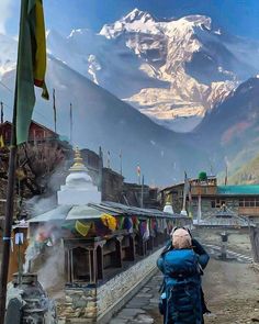 a person with a backpack standing in front of a mountain and looking into the distance