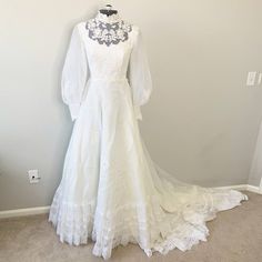 White Lace Embroidered Mock Neck Wedding Gown. Mock Neckline With Sheer Lace Upper And Embroidered Florals. Long, Sheer Puffed Sleeves With Embroidered Button Snap Cuffs. Gathered Waist, A-Line Silhouette, Back Zipper Closure. There Is No Size Listed Measurements - Shoulder To Shoulder 14.5", Pit To Pit 15.5", Waist 12.5" Pit To Wrist 19", Shoulder To Wrist 24", Hip 27" No Major Flaws, Stains, Marks Or Holes Tags: Wedding, Gown, Dress, Victorian, Romantic, Cottage Core, Bohemian, Lace, Fashion German Wedding Dress, German Wedding Traditions, White Floor Length Dress, Edwardian Wedding Dress, German Wedding, Vintage Wedding Dress Boho, Edwardian Wedding, Wedding Gown Dress, Western Wedding Dresses